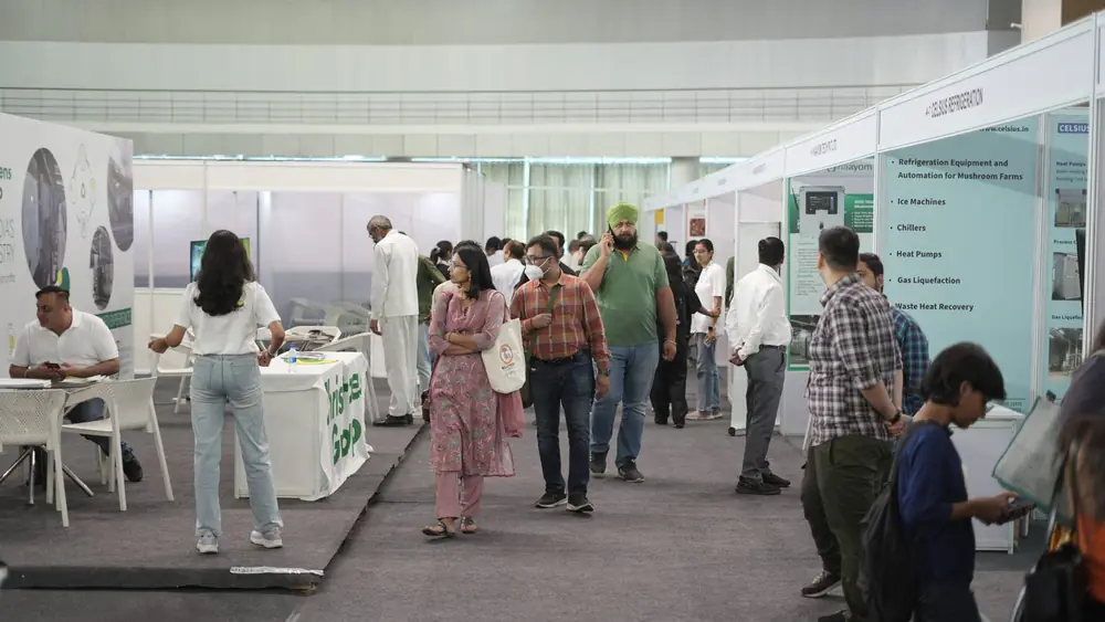Visitors walking the exhibition aisle past refrigeration and equipment stands